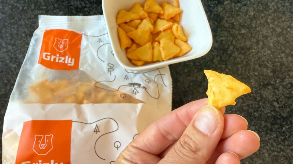 Sýrové trojhránky Grizly – originální slaný snack s jemnou chutí koření, vhodný pro večerní mlsání.